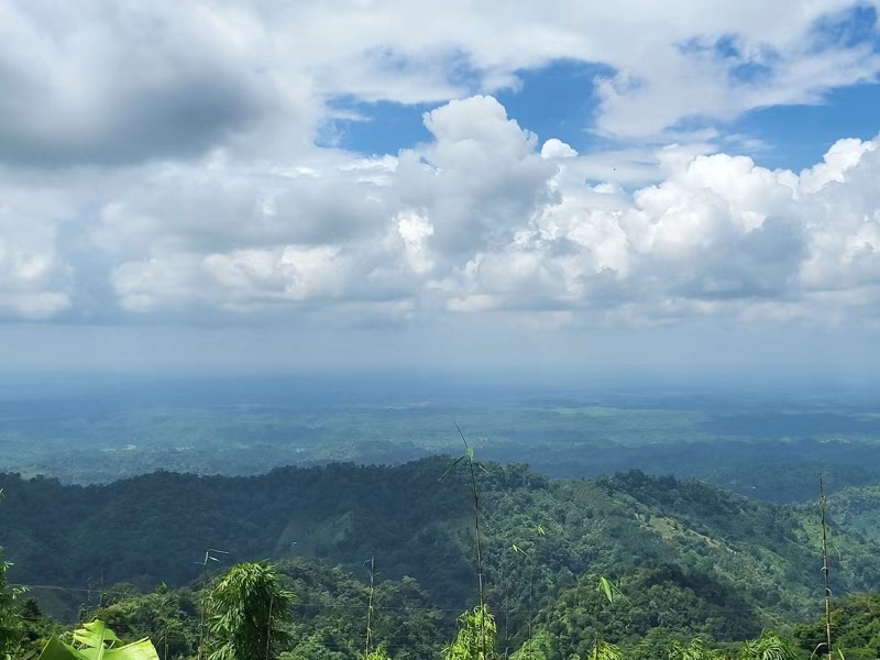 Layered forested hills fading into haze under a tall cloudy sky